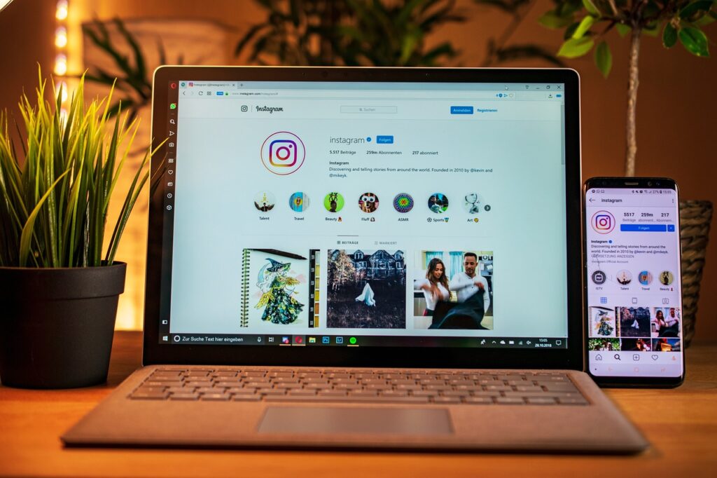laptop and smartphone on a desk showing social media icons related to influencer marketing